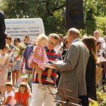 Stojący tyłem poseł Bogusław Sonik daje dyplom dziewczynce siedzącej na rękach taty. W tle widać tłum ludzi czekający na wyniki konkursu.