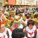 Tłum zebrał się na Małym Rynku w Krakowie. Część osób jest ubrana w stroje ludowe i trzyma bukiety zielne.