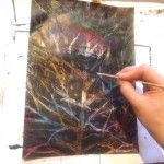 Kobieta maluje obrazek kolorowych gałęzi drzewa na czarnym tle.