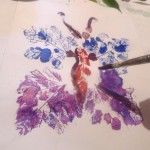 Malowanie obrazku motyla stworzonego przy pomocy liści odbitych farbą. Osoba domalowuje elementy tułowia pędzlem.