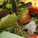 Zbliżenie na bukiet zielny zawierający jabłko, jarzębinę, kwiaty, zioła i zboża.