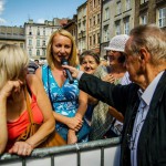 Mężczyzna podaje mikrofon kobiecie, która stoi za barierką pod sceną podczas konkursu na Małym Rynku w Krakowie.