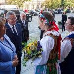 Dziewczyna i mężczyzna ubrani w stroje ludowe wręczają kwiaty Prezydentowi Bronisławowi Komorowskiemu i Pierwszej Damie.