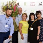 Grzegorz Małodobry, Bogusław Sonik, Liliana Sonik i dwie pozostałe jurorki stojące na tle baneru konkursowego, Bogusław Sonik trzyma bukiet zielny